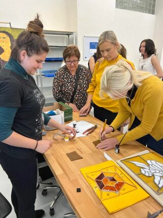 členka správnej rady nórskej Nadácie VELUX Foundation počúva pokyny sklárky Simony Majdišovej pri výrobe vitráže 